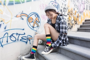 Detail of colorful rainbow striped crew socks paired with black heart logo high-top sneakers
