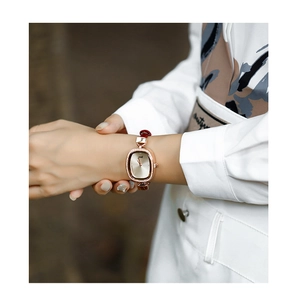 Close-up of women's vintage oval rose gold watch with red leather strap and diamond bezel