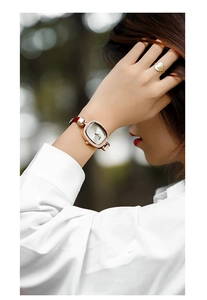 Elegant woman wearing a rose gold rectangular watch with brown leather strap in outdoor light