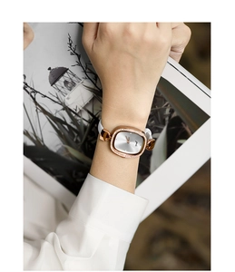 Detail of elegant rose gold oval watch with crystal bezel and white leather strap on wrist