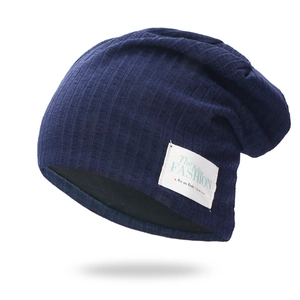Dark blue ribbed knit beanie hat with fashion label decoration on a white background