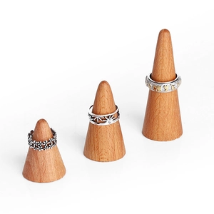 Conical wooden ring display stands with vintage silver and two-tone rings on white background
