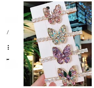 Close-up of four butterfly hair clips with colorful zircon crystals on silver metal