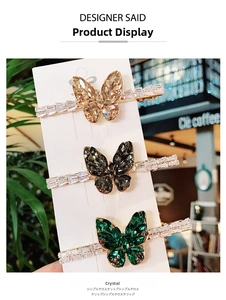Three crystal butterfly hair clips in champagne, black, and emerald on display