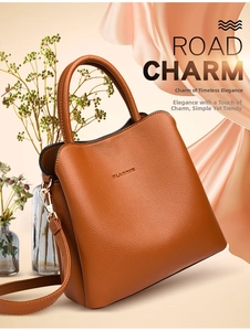 Detail view of brown lychee texture leather handbag with CLASSIC embossing and metal hardware