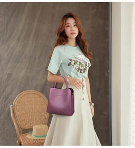 Detail of a purple PU leather handbag with CLASSIC lettering held by a model in casual wear