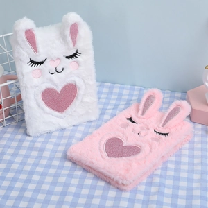 Close-up of white and pink plush rabbit notebooks with embroidered heart details