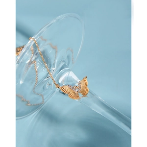 Détail macro d'un pendentif papillon doré avec zircons sur une tige en verre
