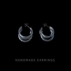 Macro shot of silver triple-layered circular hoop earrings with polished metal finish