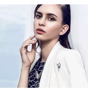 Detailed view of a blue crystal cat brooch worn on a white suit lapel for elegant styling