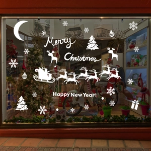 Detail of white Christmas window stickers with Santa, sleigh, and snowflakes on glass shopfront