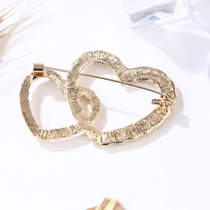 Golden double heart brooch with textured finish on minimalist white background