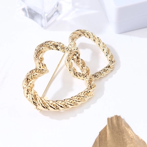 Close-up of golden double heart brooch with textured rope finish on a white background