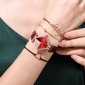 Detail of red square watch with rose gold bezel and matching fashion bracelets