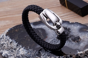 Detail of black braided leather bracelet with silver stainless steel lion head clasp