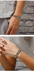 Detail of silver stainless steel curb chain bracelet on wrist with textured background