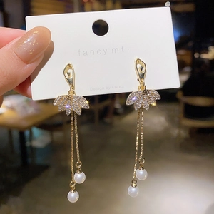 Macro view of gold ballet dancer earrings with tassels and white pearls details