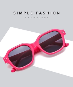 Detail of bright pink square sunglasses with rivets and dark grey lenses on geometric background