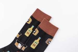 Detail of black cotton socks featuring whiskey bottle and glass patterns with brown cuffs