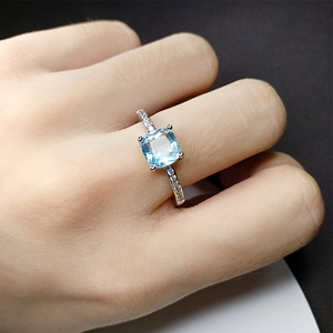 Elegant silver ring with a square light blue gemstone and pave-set side diamonds on hand