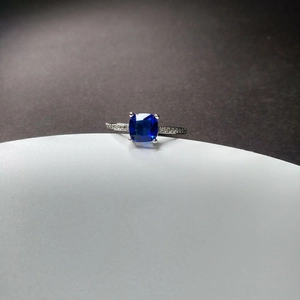 Macro detail of a square blue sapphire ring with a four-claw silver band setting