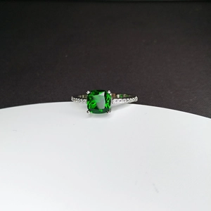 Detail shot of a square green gemstone ring with silver band and side diamond accents