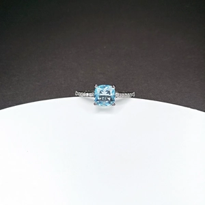 Macro shot of silver ring featuring a large light blue cushion-cut sapphire and side diamonds