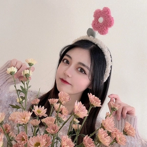 Cute lamb wool headband with a pink plush flower, worn by a woman in a sweet style