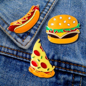 Close-up of enamel fast food pins including hot dog, burger, and pizza on denim jacket