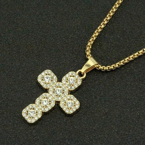 Collier pendentif croix dorée avec strass scintillants sur fond noir texturé