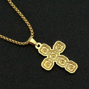 Vue macro montrant l'arrière détaillé d'un pendentif croix dorée serti de cristaux