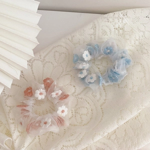 Detailed macro view of embroidered floral patterns on sheer organza scrunchies in pastel colors