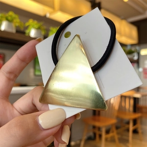 Minimalist gold triangle metal hair tie with black elastic band on display card