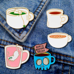 Detail of five coffee-themed enamel pins featuring skulls and cats on denim fabric
