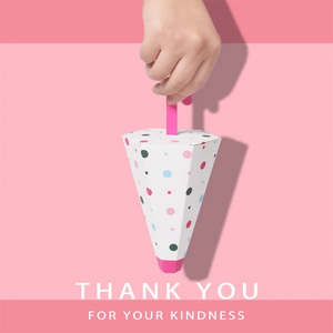 Close-up of hand holding a polka dot umbrella-shaped candy paper gift box with handle