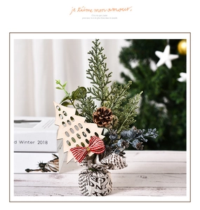 Detail of a mini Christmas tree with pine cones, red berries and festive bow decoration