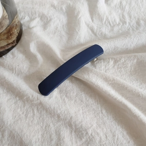 Macro detail of dark blue matte acrylic hair clip with silver metal spring buckle