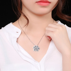 Elegant silver paw pendant necklace with sparkling diamonds worn by a model on black background