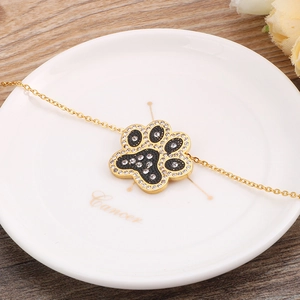 Elegant gold chain necklace featuring a crystal-studded black paw print pendant design