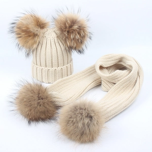 Detail of beige chunky knit hat and scarf set with four large fluffy fur pom-poms