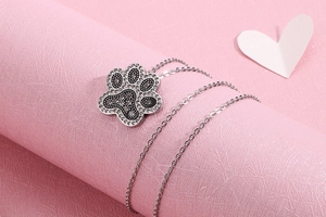 Detail shot of sparkling rhinestone-studded paw pendant on a silver necklace
