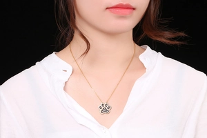 Detailed view of a gold paw print pendant necklace with black and white rhinestones