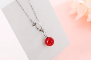 Detailed close-up of a stainless steel necklace with a glossy red spherical pendant