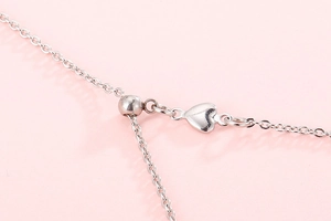 Macro shot of silver necklace clasp featuring a delicate heart-shaped pendant detail