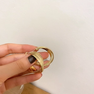 Detail of gold multi-layered intertwining lines on a C-shaped geometric hoop earring