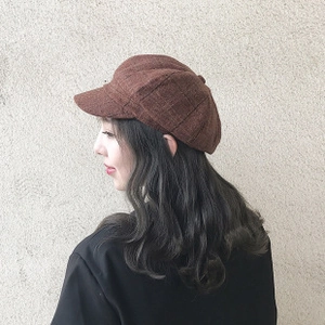Close-up of brown plaid beret hat with retro British pattern and textured fabric detail