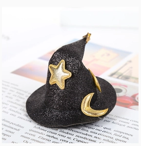 Detailed close-up of a black glittery witch hat hair clip with gold star and moon patterns