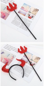 Close-up of red sequined devil horns and pitchfork set on vintage magazine background