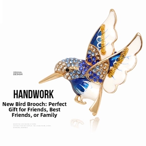 Macro shot of colorful rhinestone hummingbird brooch with blue enamel wings and gold plating