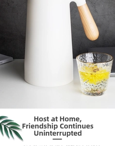 Modern white thermal carafe with wood handle and textured glass cup on table
